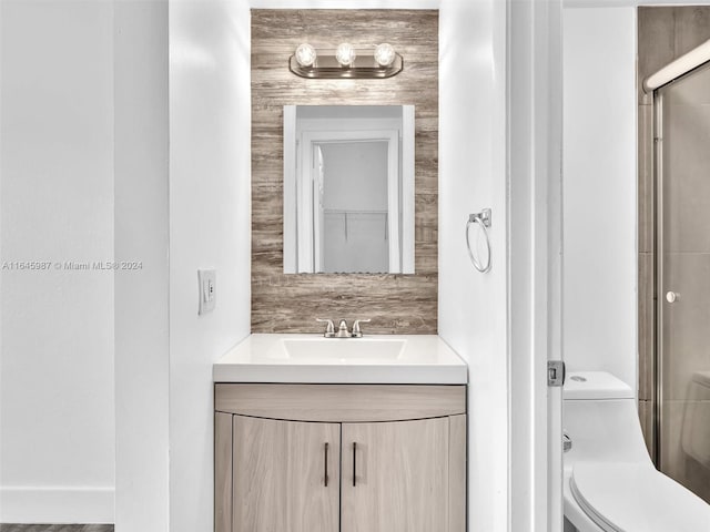 bathroom featuring toilet, a shower with door, and vanity