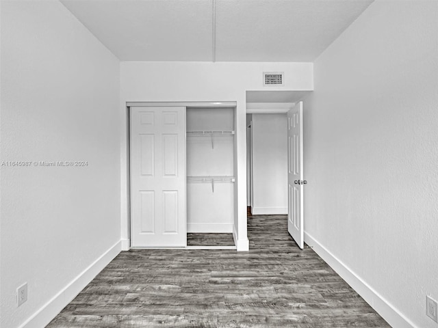 unfurnished bedroom featuring a closet and hardwood / wood-style flooring