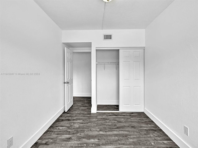 unfurnished bedroom featuring dark hardwood / wood-style flooring and a closet