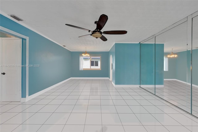 tiled empty room with ceiling fan with notable chandelier and ornamental molding