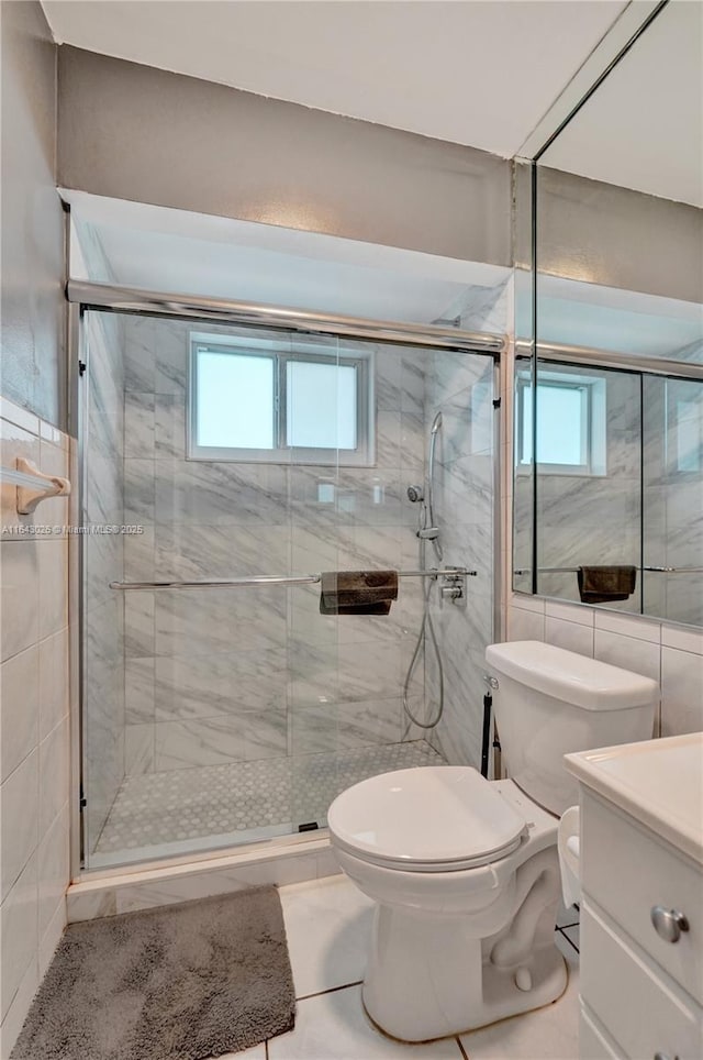 bathroom with tile patterned floors, vanity, an enclosed shower, and toilet