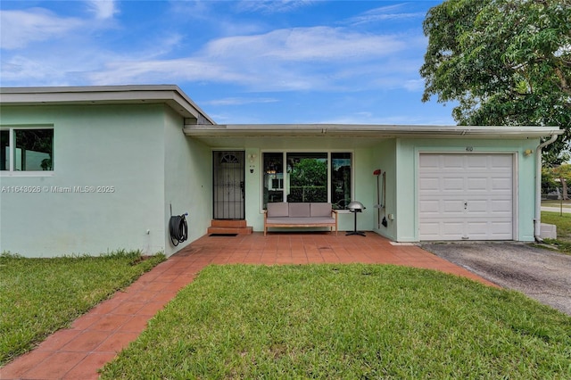 entrance to property with covered porch, a garage, and a yard