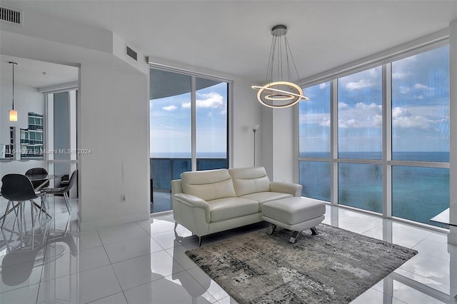 living room with floor to ceiling windows, a chandelier, a water view, and light tile patterned floors