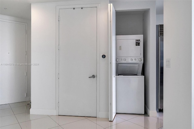 clothes washing area featuring stacked washing maching and dryer and light tile patterned floors