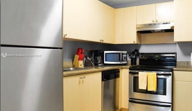 kitchen with stainless steel appliances, dark countertops, a sink, and under cabinet range hood