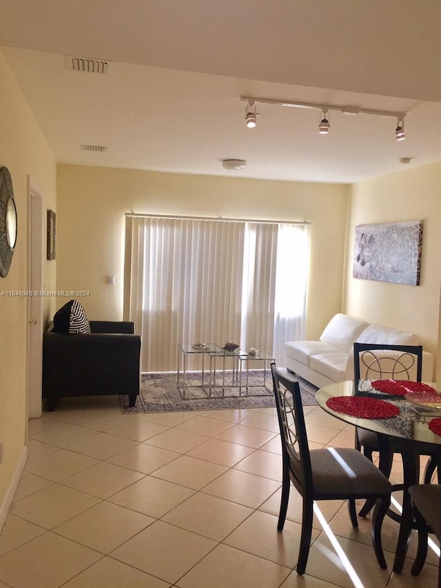 dining space featuring rail lighting, visible vents, and light tile patterned flooring