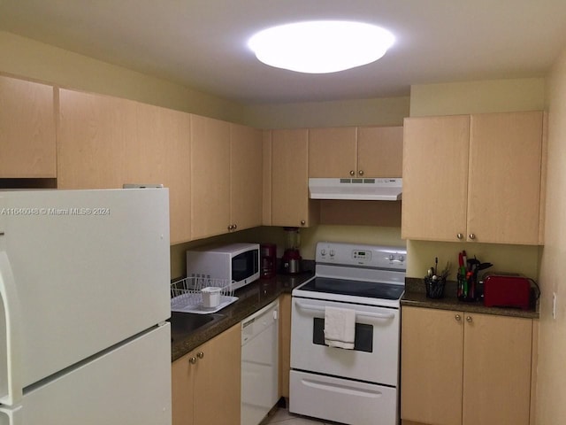 kitchen with white appliances, dark countertops, light brown cabinets, and under cabinet range hood