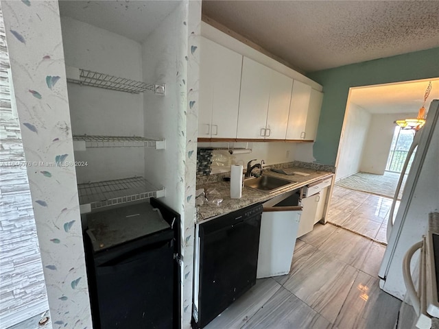 kitchen with white cabinetry, stainless steel refrigerator, sink, light tile patterned floors, and black dishwasher