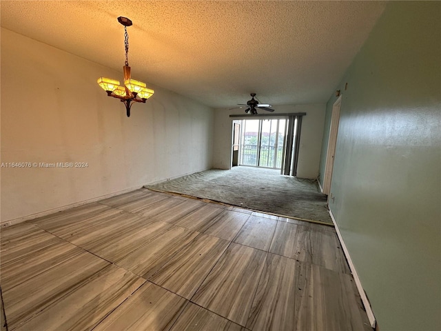 carpeted spare room featuring a textured ceiling and ceiling fan with notable chandelier