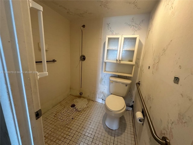 bathroom featuring toilet, tiled shower, and tile patterned floors