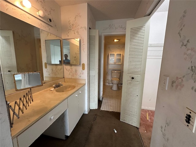 bathroom featuring toilet, a textured ceiling, and vanity