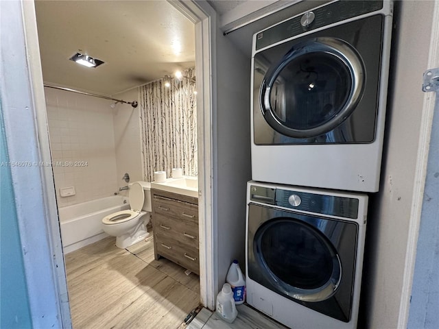 laundry area featuring stacked washer / dryer and light hardwood / wood-style flooring