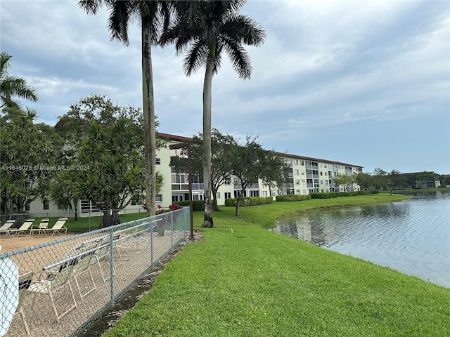 view of property's community with a lawn and a water view