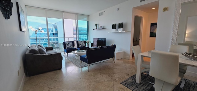 living room with a wall of windows, visible vents, and baseboards