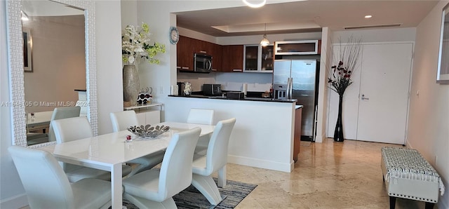 kitchen featuring kitchen peninsula, pendant lighting, dark brown cabinets, and stainless steel appliances