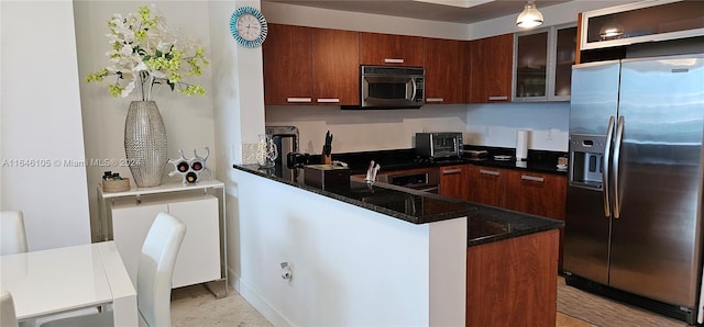 kitchen with dark stone countertops, kitchen peninsula, and appliances with stainless steel finishes