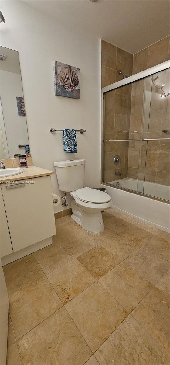 full bathroom featuring vanity, enclosed tub / shower combo, and toilet