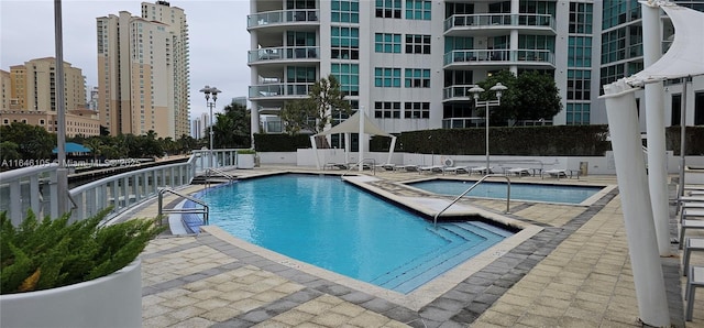 pool featuring a patio area, a view of city, and fence