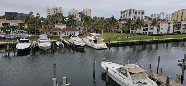 view of dock with a view of city, a lawn, and a water view