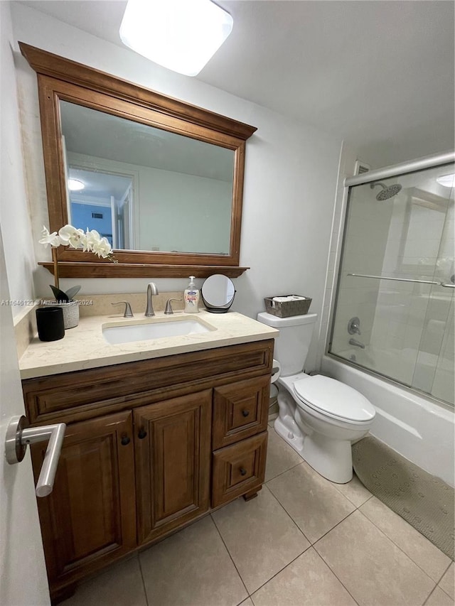 bathroom with toilet, tile patterned flooring, enclosed tub / shower combo, and vanity