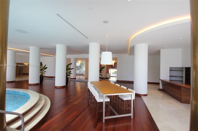 dining space featuring dark wood-style flooring, baseboards, and ornate columns