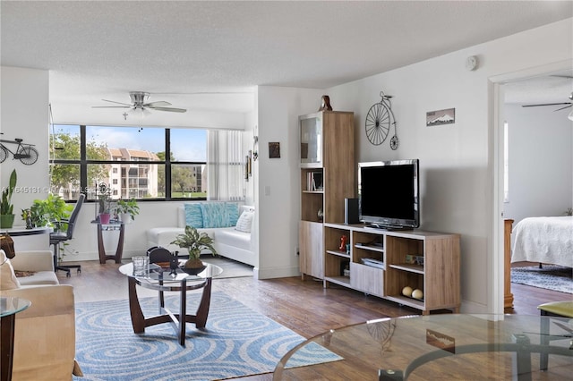 living room featuring a textured ceiling, ceiling fan, and wood-type flooring