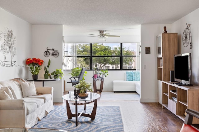 living room with hardwood / wood-style floors, ceiling fan, and a textured ceiling