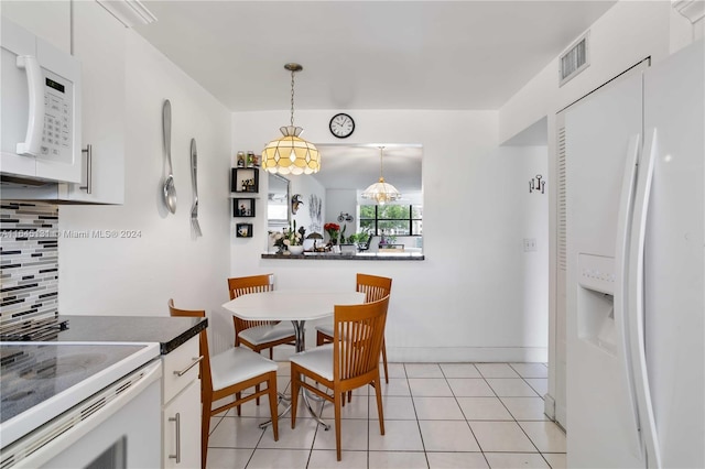 kitchen with light tile patterned flooring, decorative backsplash, white appliances, white cabinetry, and hanging light fixtures