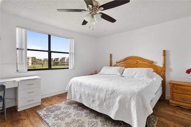 bedroom with a textured ceiling, ceiling fan, and dark hardwood / wood-style flooring