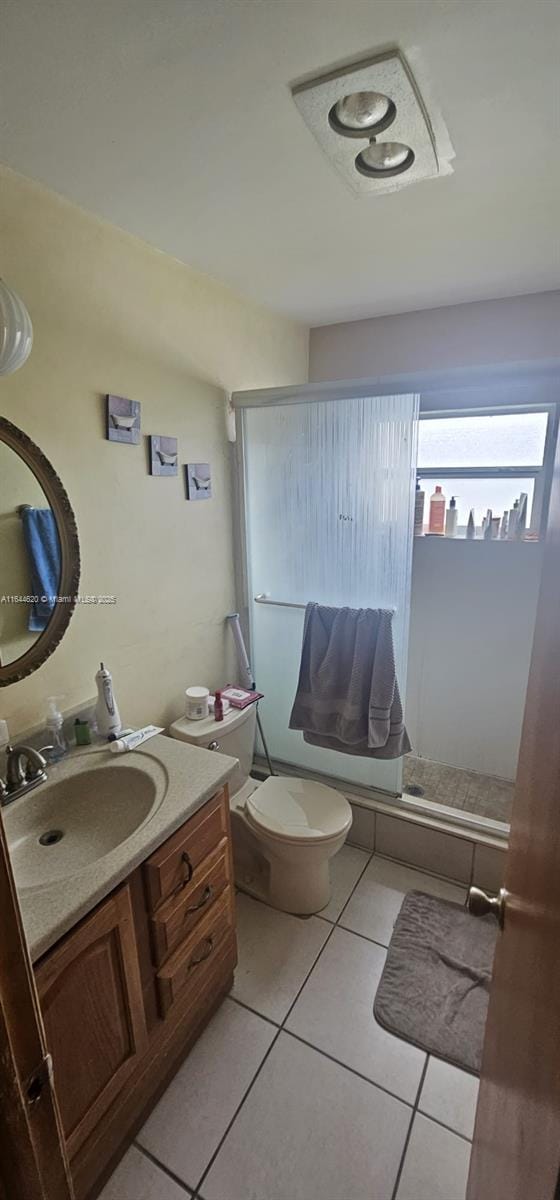 full bathroom with enclosed tub / shower combo, vanity, tile patterned floors, and toilet