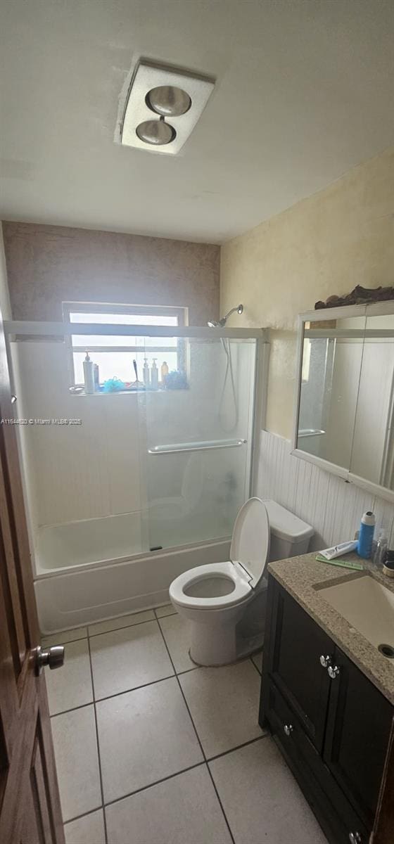 full bathroom with tile patterned flooring, vanity, combined bath / shower with glass door, and toilet