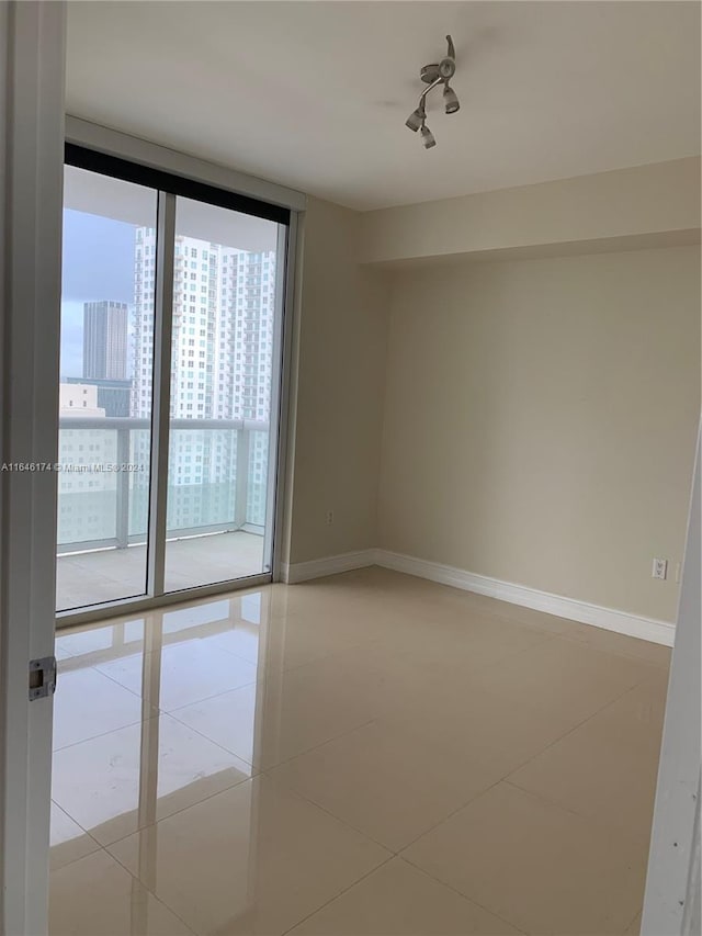 tiled empty room featuring a wall of windows