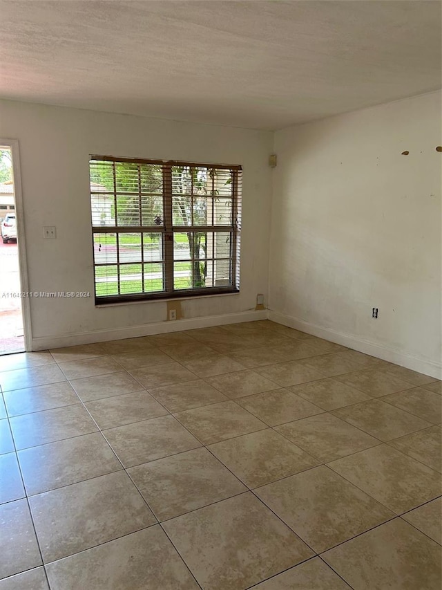 empty room featuring plenty of natural light, light tile patterned floors, and a textured ceiling