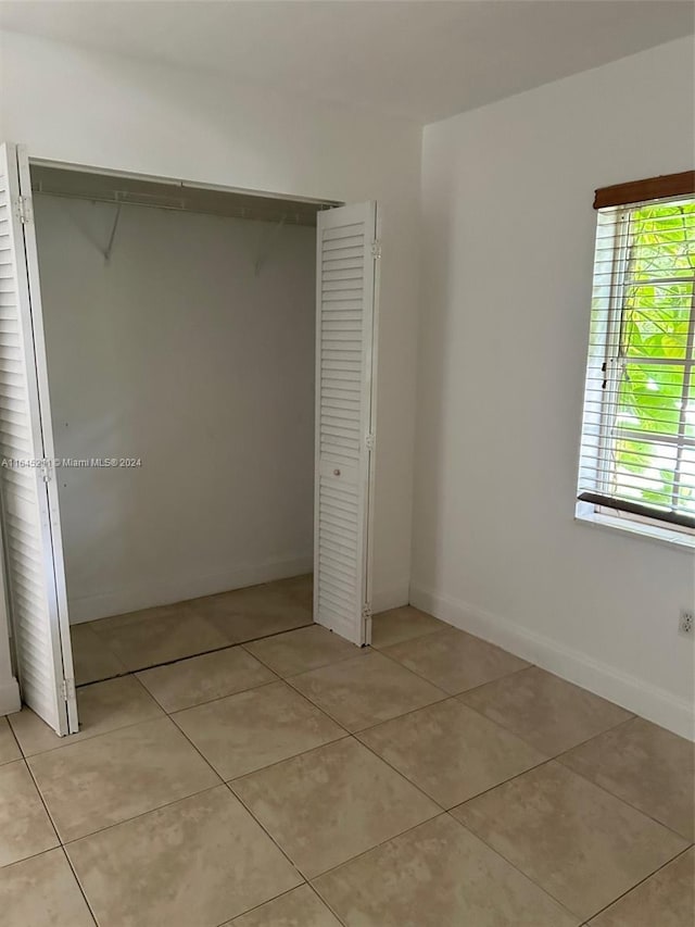 unfurnished bedroom featuring a closet and light tile patterned floors