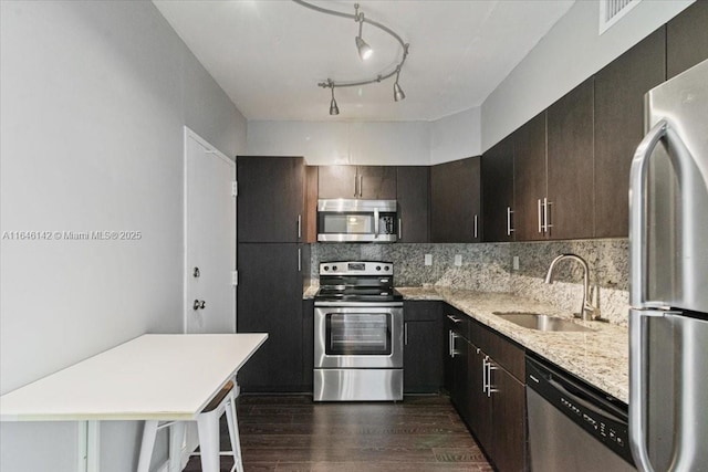 kitchen with backsplash, sink, dark brown cabinets, a kitchen bar, and stainless steel appliances