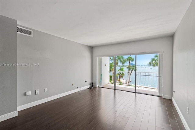 unfurnished room with dark hardwood / wood-style flooring and a water view