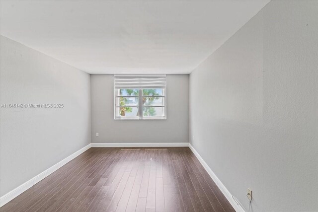 empty room with dark hardwood / wood-style flooring