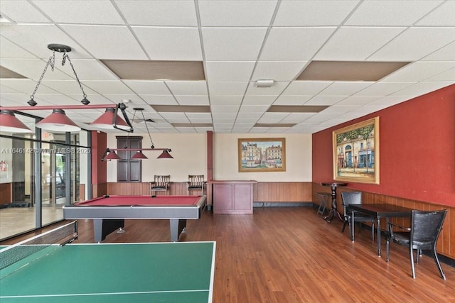 rec room with a drop ceiling, wood walls, wood-type flooring, and billiards