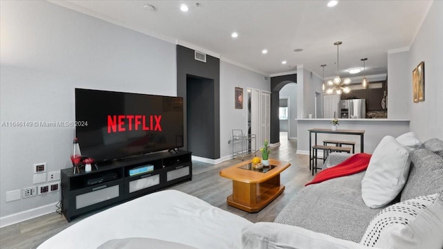 living room featuring a notable chandelier, ornamental molding, and wood-type flooring