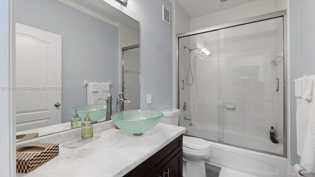 full bathroom featuring toilet, vanity, and bath / shower combo with glass door