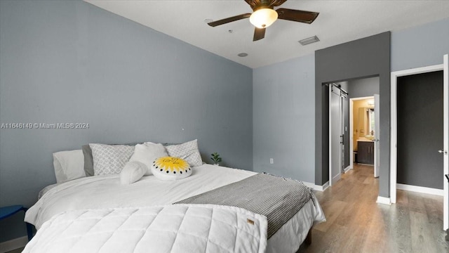 bedroom with ceiling fan, ensuite bath, and hardwood / wood-style floors