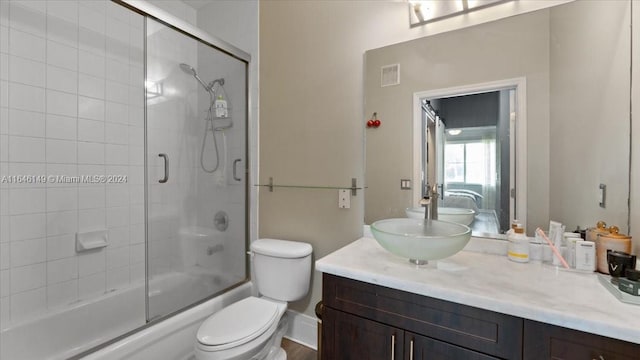 full bathroom with toilet, vanity, and enclosed tub / shower combo