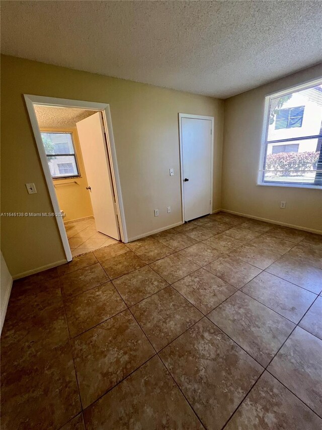 unfurnished bedroom with tile patterned flooring and a textured ceiling