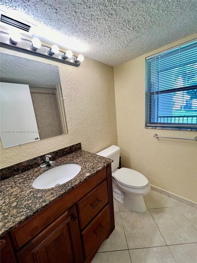 bathroom with toilet, a textured ceiling, tile patterned floors, and vanity