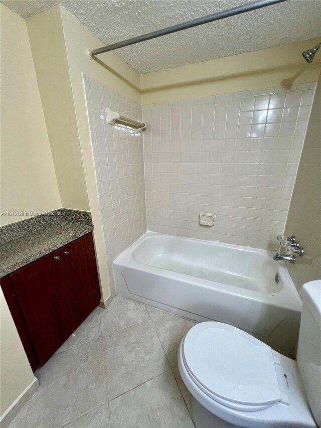 full bathroom with tile patterned flooring, toilet, a textured ceiling, and tiled shower / bath combo