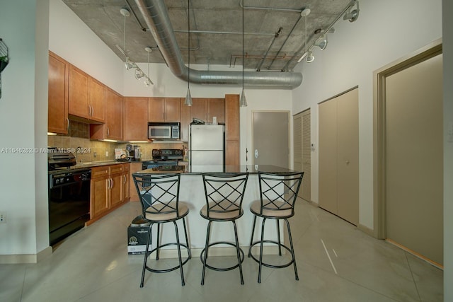 kitchen featuring black appliances, decorative backsplash, a kitchen breakfast bar, and a kitchen island