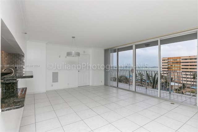 tiled empty room featuring a water view, expansive windows, and ornamental molding