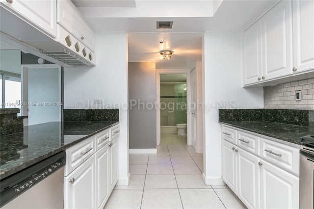 kitchen featuring light tile patterned floors, dark stone countertops, stainless steel appliances, and white cabinets