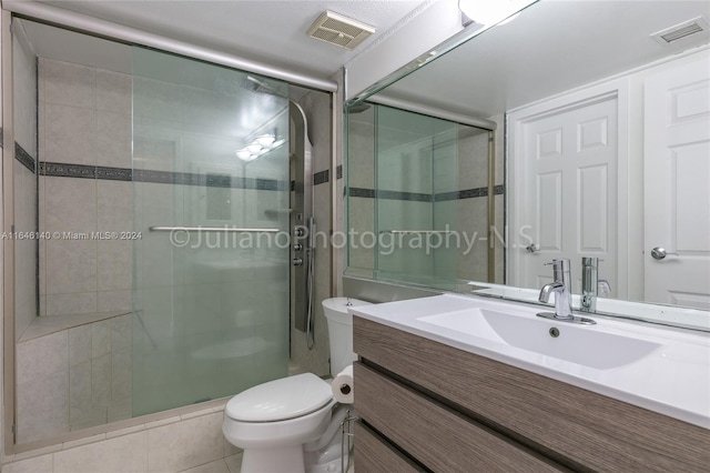 bathroom with vanity, tile patterned flooring, toilet, and a shower with door