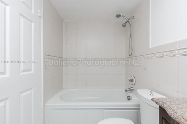 full bathroom featuring vanity, tile walls, toilet, and tiled shower / bath combo